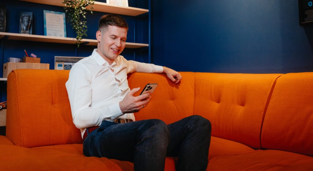 Man sitting on a couch and holding a phone in his hand.